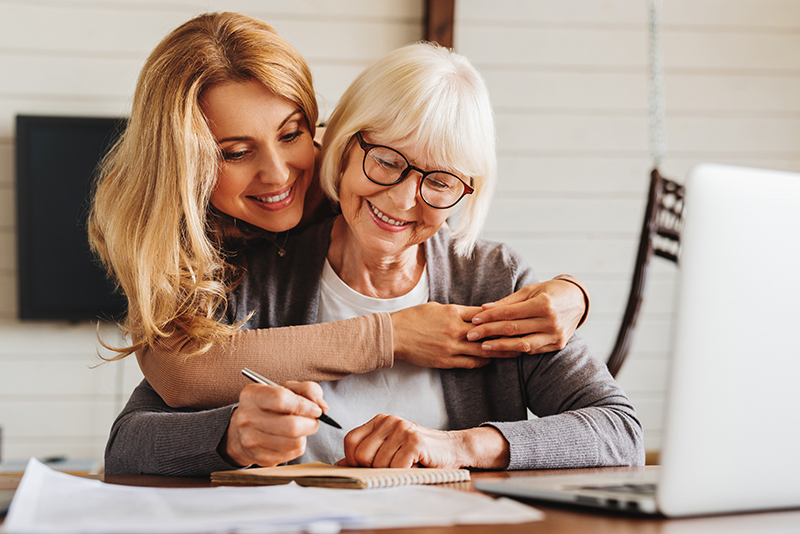 Adult daughter helping senior woman complete form at home